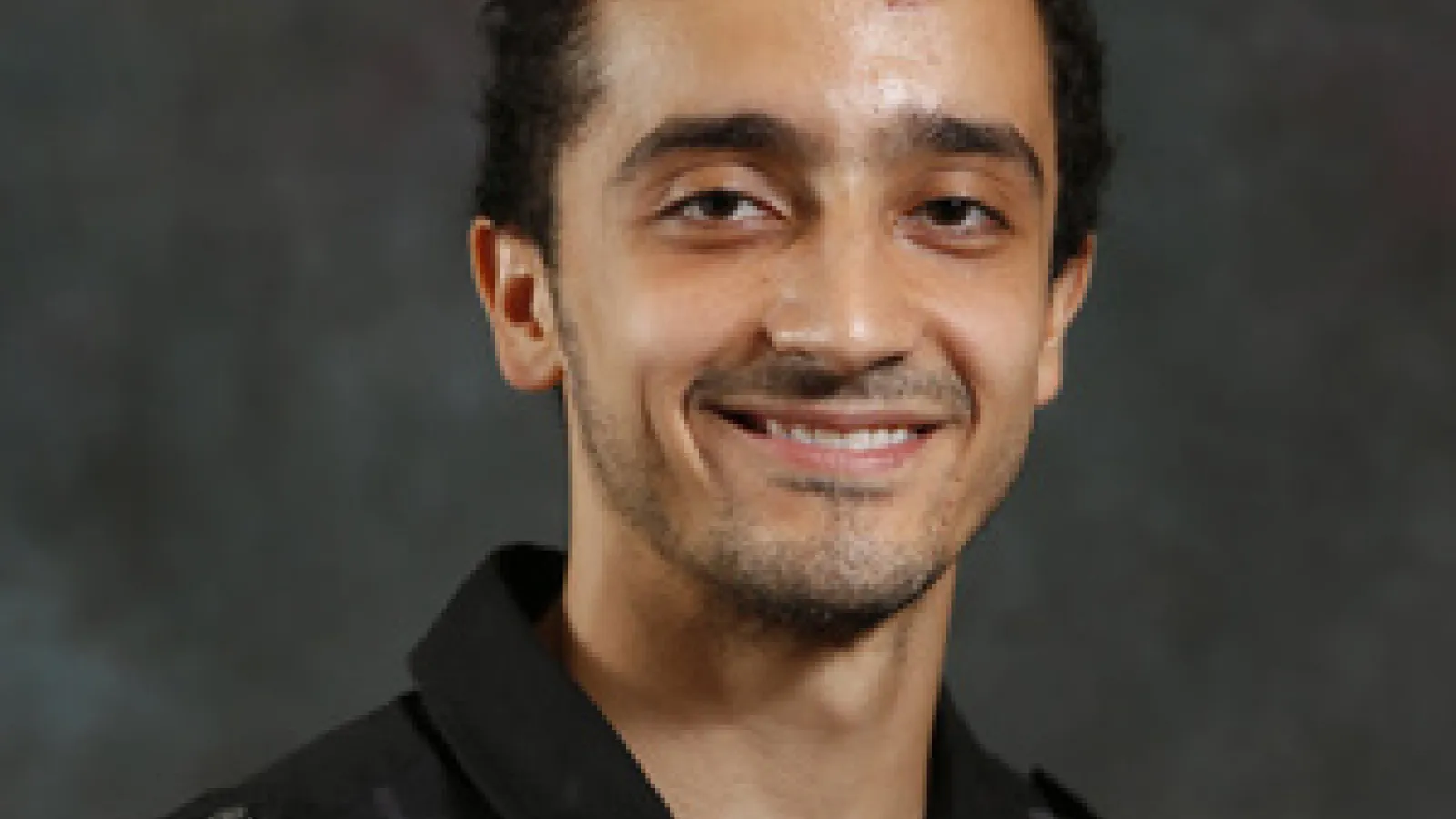 Male graduate student smiles at camera
