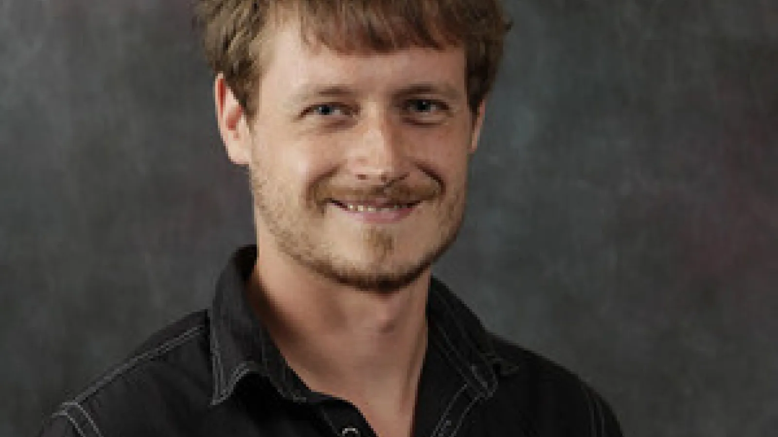 Young man with read hair, smiling at camera