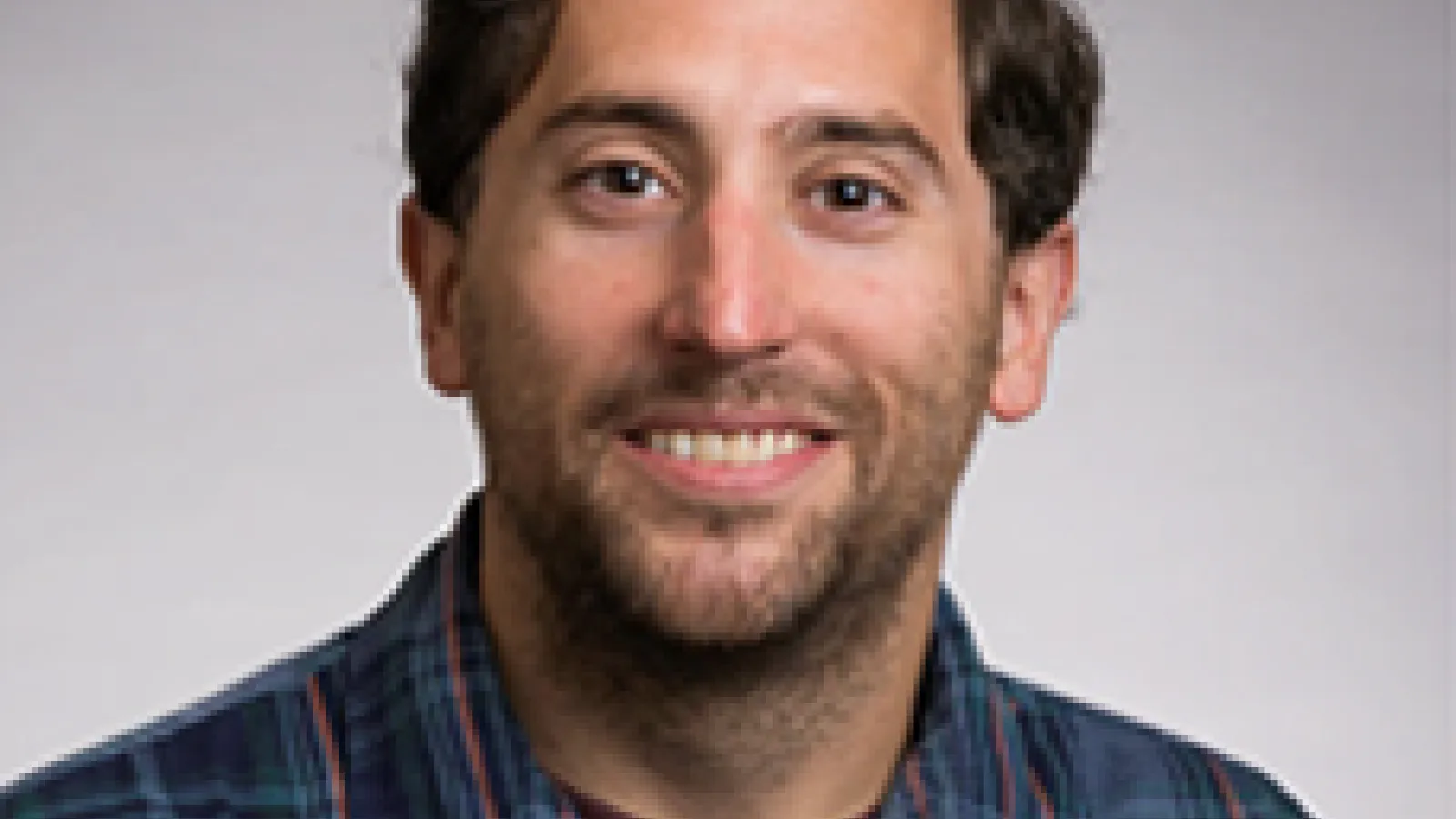 Young white man with brown hair smiling at camera