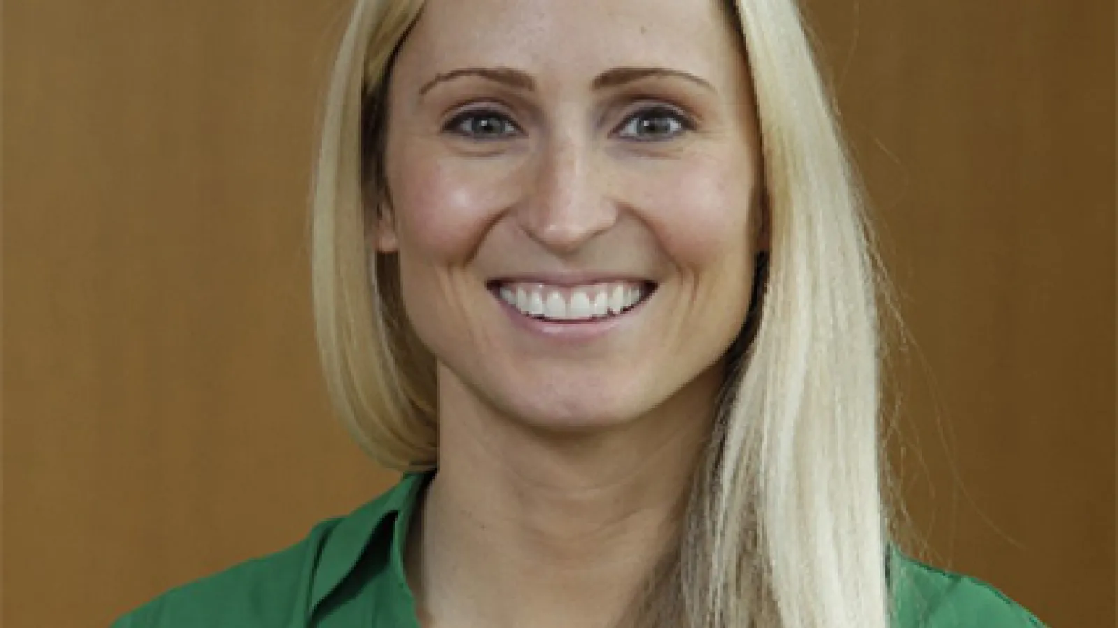 Image of white woman with blond hair, wearing a green blouse smiling at the camera