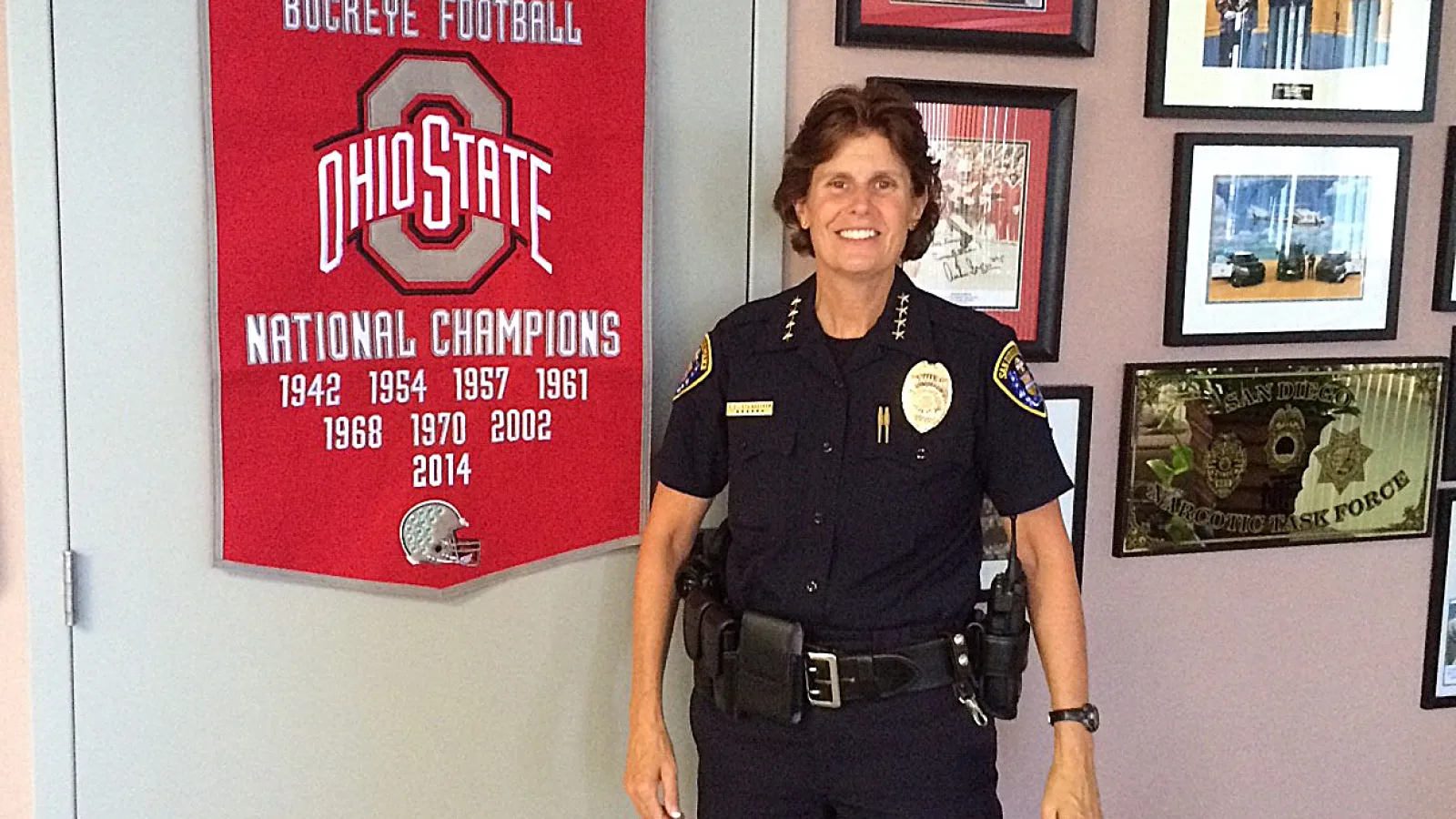 White female police officer standing by OSU memorabilia 